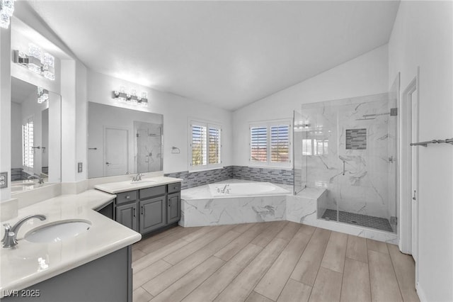 bathroom with wood tiled floor, a marble finish shower, lofted ceiling, a bath, and vanity