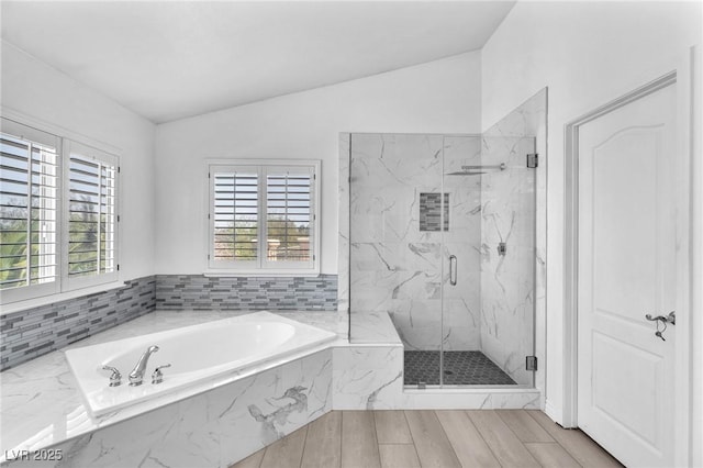 full bath featuring a marble finish shower, wood finish floors, a bath, and lofted ceiling