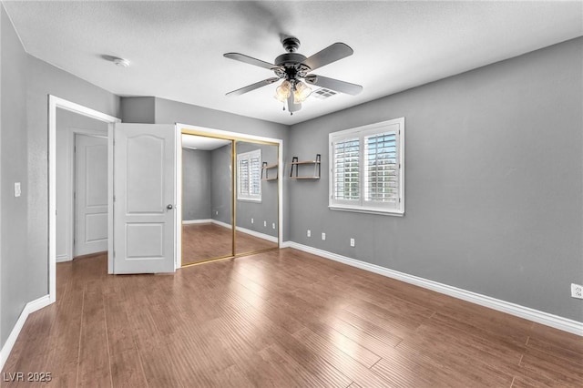 unfurnished bedroom with visible vents, baseboards, wood finished floors, a closet, and a ceiling fan