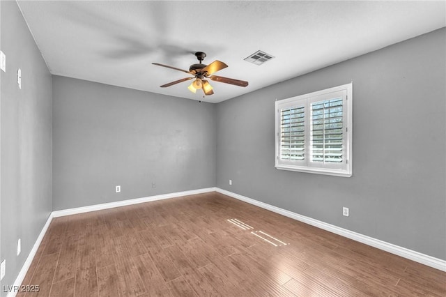 unfurnished room featuring baseboards, wood finished floors, visible vents, and ceiling fan