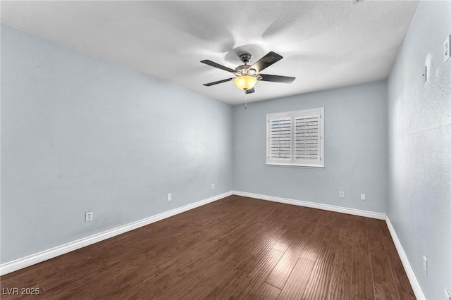 unfurnished room featuring dark wood finished floors, a ceiling fan, and baseboards