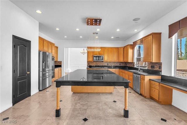 kitchen with dark countertops, backsplash, a center island, stainless steel appliances, and a sink