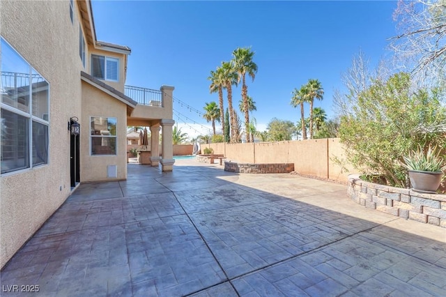 view of patio featuring a balcony and a fenced backyard