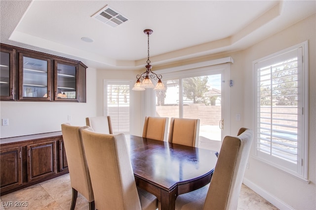 dining area with a tray ceiling, visible vents, and baseboards