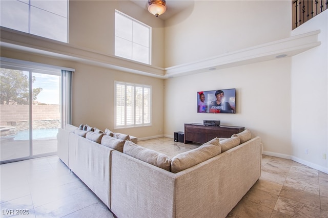 living room featuring a high ceiling, baseboards, and a wealth of natural light