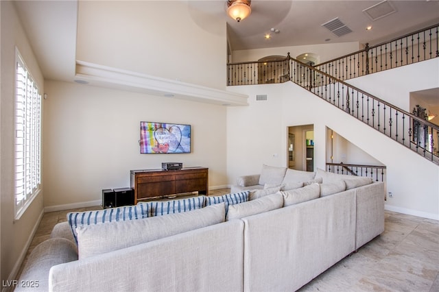 living room with a towering ceiling, visible vents, and a wealth of natural light