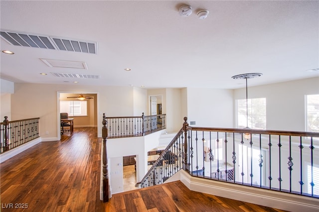 hallway with recessed lighting, visible vents, wood-type flooring, and an upstairs landing