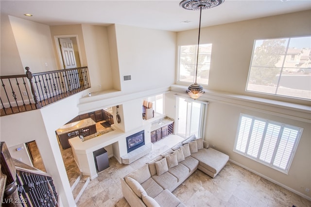 living room with a glass covered fireplace, recessed lighting, visible vents, and baseboards