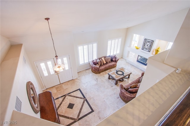 living room featuring visible vents, baseboards, a glass covered fireplace, and vaulted ceiling