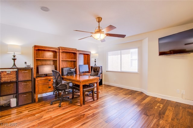 office space with baseboards, light wood-style floors, and a ceiling fan