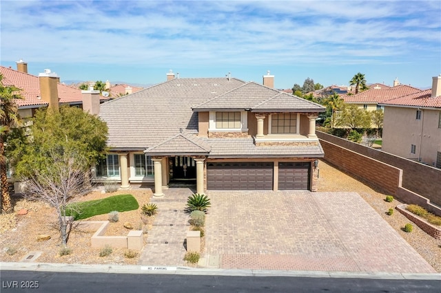 view of front of property featuring stucco siding, a tile roof, decorative driveway, fence, and a garage