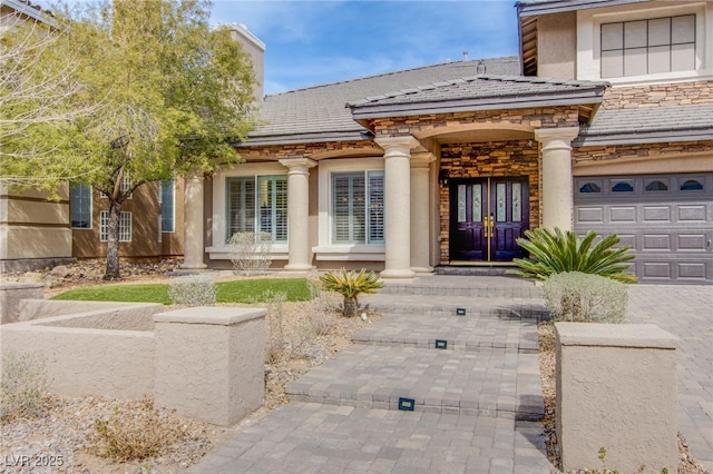 entrance to property with stone siding, stucco siding, french doors, and a garage