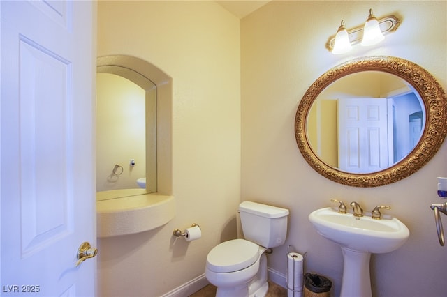 bathroom featuring toilet, baseboards, and a sink