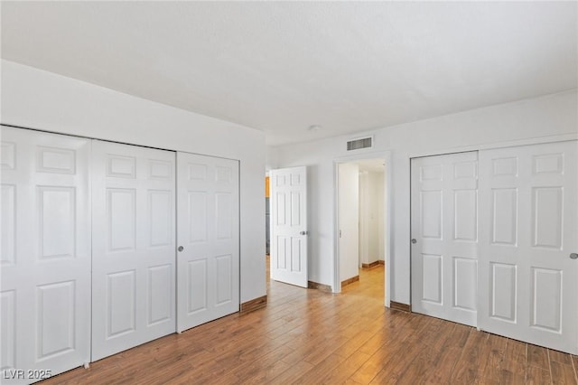 unfurnished bedroom with baseboards, visible vents, and wood finished floors