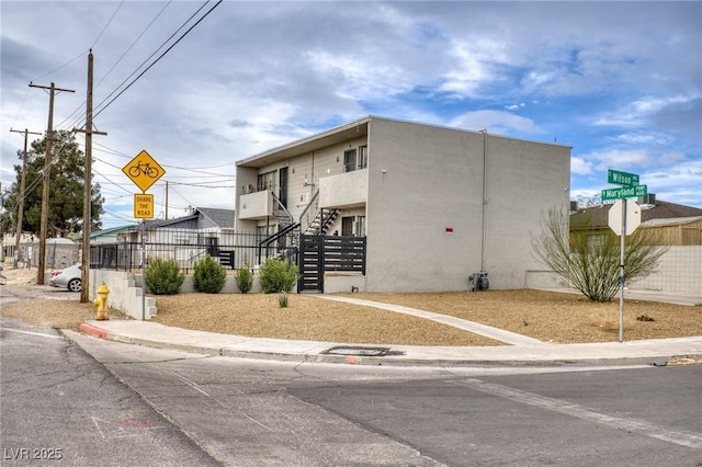 view of building exterior with stairway and fence