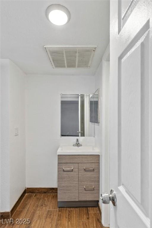 bathroom featuring baseboards, visible vents, wood finished floors, and vanity