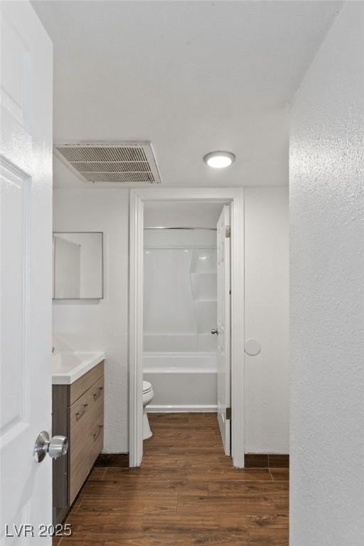 full bath featuring visible vents, toilet, wood finished floors, tub / shower combination, and vanity