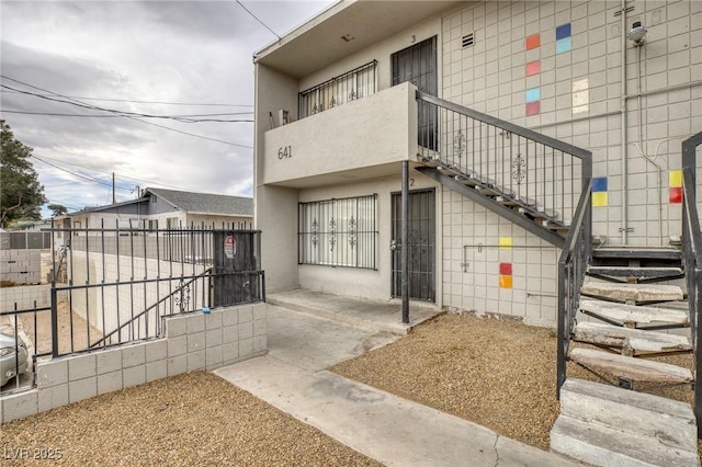 exterior space with a patio area, fence, a balcony, and stucco siding