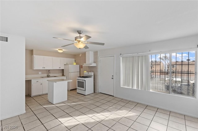 kitchen with white appliances, a sink, white cabinetry, light countertops, and wall chimney exhaust hood