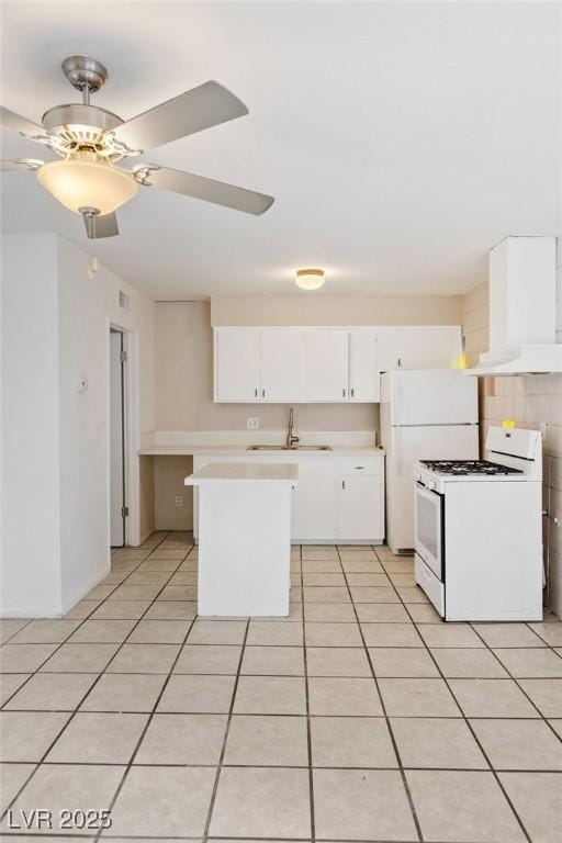 kitchen featuring light tile patterned floors, white appliances, a sink, light countertops, and wall chimney range hood