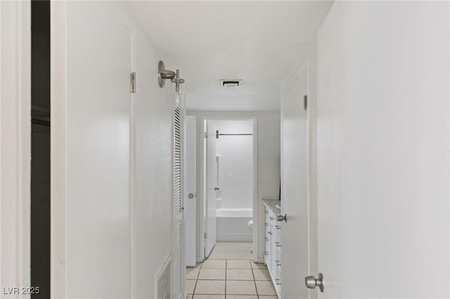 hall featuring visible vents and light tile patterned floors