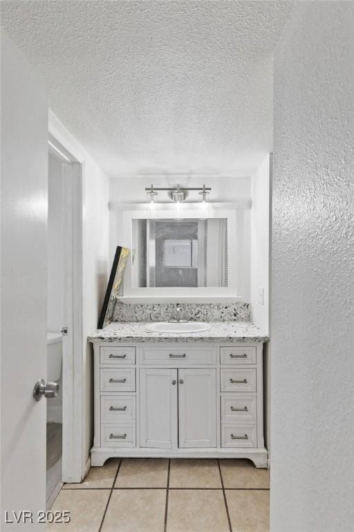 bathroom with a textured wall, tile patterned flooring, a textured ceiling, and vanity