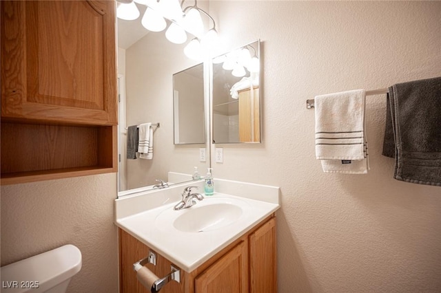 half bathroom with a textured wall, vanity, and toilet