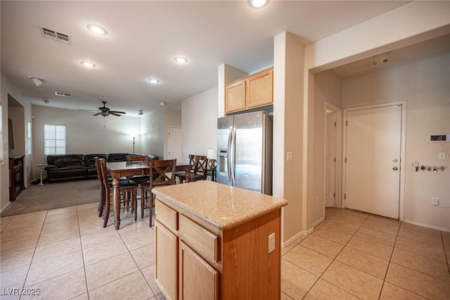 kitchen with light tile patterned floors, visible vents, open floor plan, a kitchen island, and stainless steel fridge with ice dispenser