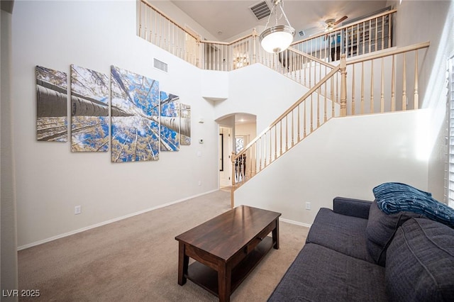 living room with carpet floors, arched walkways, visible vents, and baseboards