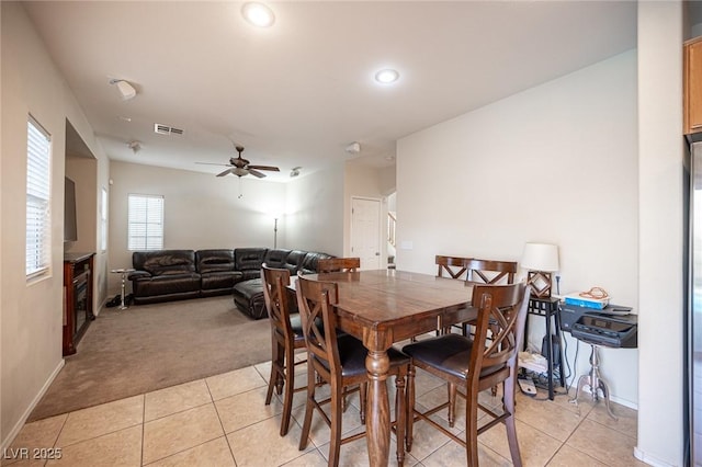 dining space with light carpet, light tile patterned floors, ceiling fan, and visible vents