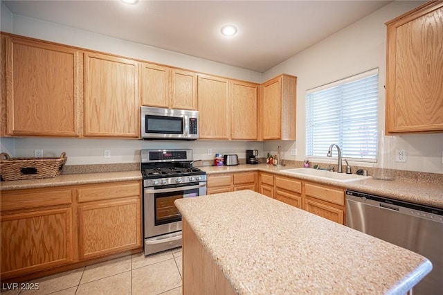 kitchen featuring light tile patterned floors, light countertops, stainless steel appliances, light brown cabinetry, and a sink