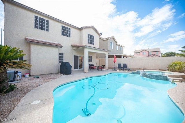 view of swimming pool with a patio area, a pool with connected hot tub, and fence