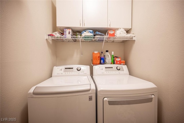 washroom with cabinet space, washer and clothes dryer, and a textured wall