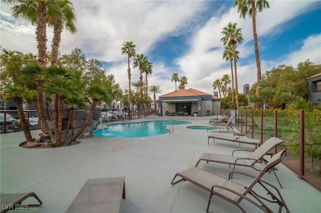 pool with a patio area and fence