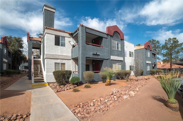 view of front of home with stairs, a chimney, and stucco siding