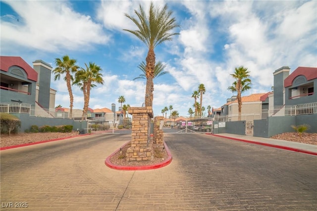 view of road featuring curbs, a gated entry, a residential view, and a gate