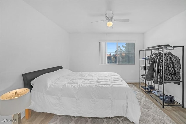 bedroom with ceiling fan, wood finished floors, and baseboards