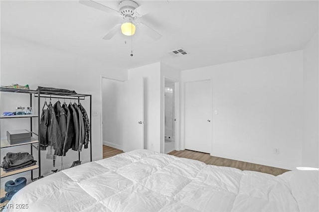 bedroom featuring a ceiling fan, visible vents, and wood finished floors