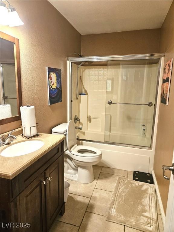 full bath with a textured wall, tile patterned flooring, toilet, shower / bath combination with glass door, and vanity