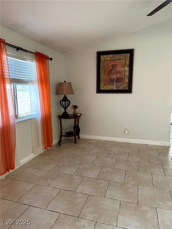 unfurnished room with ceiling fan, light tile patterned floors, and baseboards