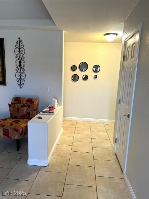 hallway with light tile patterned flooring and baseboards