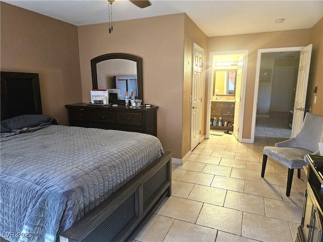 bedroom with ensuite bathroom, baseboards, and light tile patterned floors