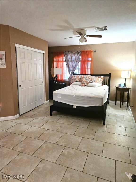 bedroom featuring light tile patterned floors, ceiling fan, baseboards, and a closet