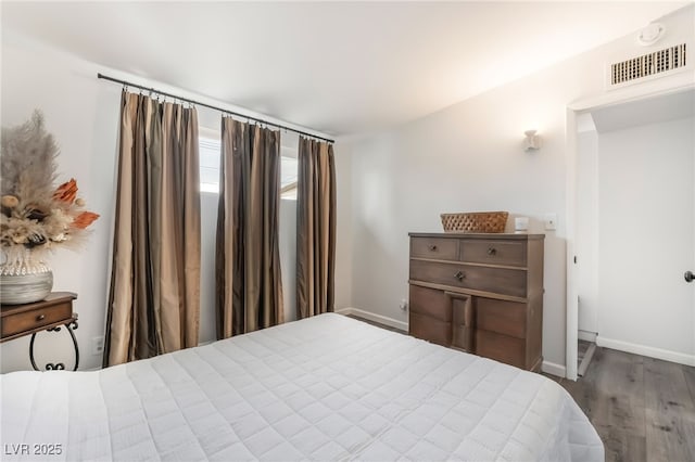 bedroom featuring visible vents, baseboards, and wood finished floors