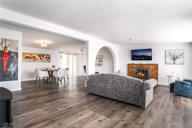 living room with a fireplace, baseboards, and wood finished floors