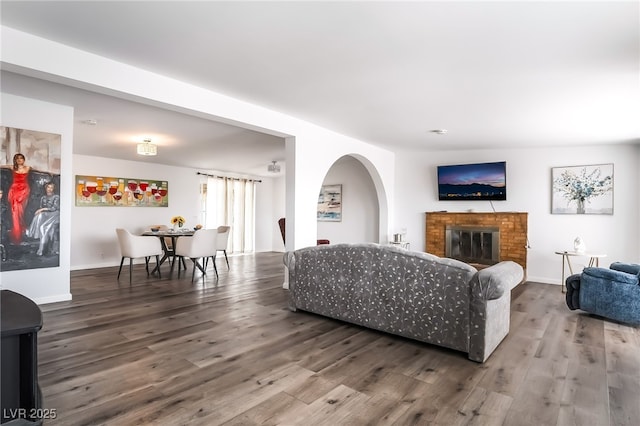 living room with a fireplace, baseboards, and wood finished floors