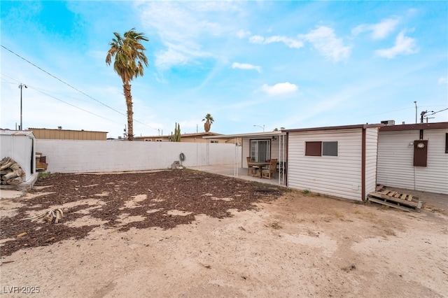 back of property featuring an outbuilding, a patio, and fence