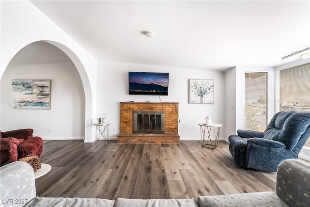 living area with a fireplace, baseboards, and wood finished floors