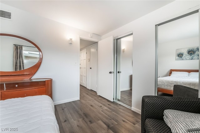 bedroom with visible vents, baseboards, and wood finished floors