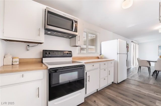 kitchen featuring electric range, stainless steel microwave, light countertops, and freestanding refrigerator